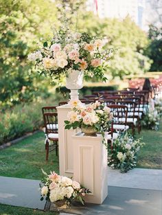 an outdoor ceremony setup with flowers and greenery in vases on the side walk