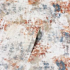 a roll of tape is laying on top of an old, faded rug with red and blue colors