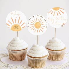 three cupcakes with white frosting on top of a doily covered table