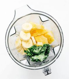 bananas, lettuce and other vegetables in a blender on a white background