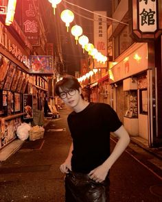 a young man is standing in the middle of an alleyway at night with his hands on his hips