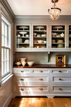 a kitchen with lots of white cabinets and wood flooring on top of wooden floors