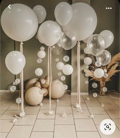 balloons and streamers are on the floor in front of a vase with dried grass