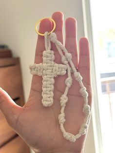 a hand holding a small crocheted cross in it's palm with a gold ring