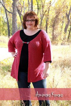 a woman standing in the grass wearing a red cardigan and black top with her hands on her hips