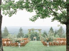 an outdoor ceremony setup with wooden chairs and greenery