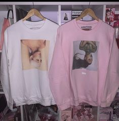 two sweatshirts hanging up on a rack in a store