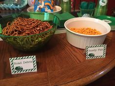 there is a bowl of food on the table next to other plates and cups with name tags