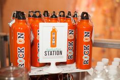 six orange soda bottles sitting on top of a white shelf in front of water bottles