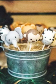 some cake pops are in a bucket with animals on them and one has a monkey