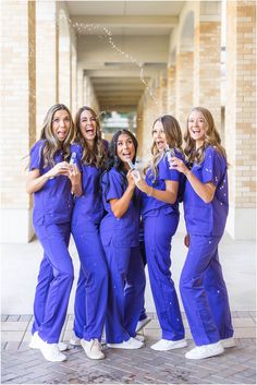 a group of women standing next to each other wearing blue scrubs and white shoes