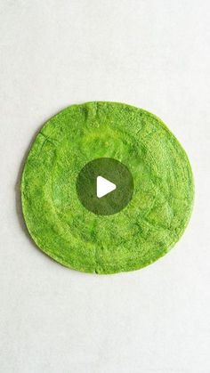 a green circular object with a play button in the center on a white table top