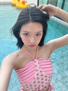 a woman in a pink top standing next to a swimming pool