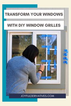 a woman is painting the windows with blue tape