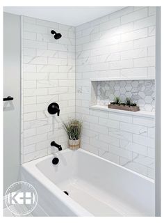 a white bathroom with black fixtures and marble tiles on the walls, along with a plant