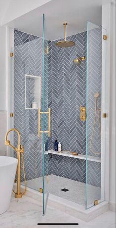 a walk in shower sitting next to a bathtub with a glass door and gold faucet