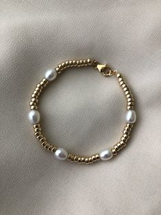 A modern gold and pearl bracelet that looks great on its own or stacked.  A statement piece with a classic style. Features lustrous pearls + high quality 14kt gold filled beads and closures. Measures approx. 7" Comes packaged in a cotton pouch and resealable bag.  ---------------------------------------------------------------------------- >> Check out the entire shop here: https://www.etsy.com/ca/shop/standingoaccessories >> Follow is on Instagram:  http://instagram.com/standing_o_accessories P Modern Gold Pearl Bracelet, Modern Gold Pearl Bracelets, Modern Gold Pearl Bracelet As Gift, Adjustable Gold Pearl Bracelet In Modern Style, Gold Minimalist Pearl Bracelet With Gold Beads, Pearl Gold Bracelet, Modern Pearl Jewelry, Gold Bead Bracelet, Gold Pearl Bracelet