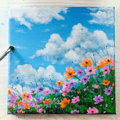 an acrylic painting of colorful flowers on a blue sky with fluffy white clouds