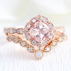 Artfully sculpted peach sapphire engagement ring features a 6x6mm cushion cut conflict free cultured champagne peach sapphire in our signature vintage floral diamond and finished in the diamond scalloped band to complete its distinctive and elegant look. Adore your future bride with this vintage halo diamond sapphire ring. It can be made in your choice of platinum or 18k or 14k yellow, rose, or white gold. A matching bridal ring set is available.** The listing price is for one engagement ring on Peach Sapphire Engagement Ring Rose Gold, Peach Engagement Ring, Sapphire Engagement Ring Rose Gold, Unique Sapphire Rings, Peach Sapphire Rings, Pink Sapphire Diamond Ring, Diamond Alternative Engagement Ring, Peach Sapphire Engagement Ring, Sapphire Engagement Ring Set