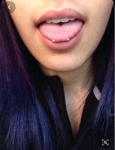 a woman with purple hair and piercings on her tongue