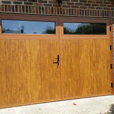 two wooden garage doors in front of a brick building