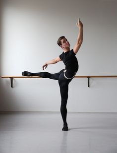 a man in black shirt and leggings doing a ballet pose