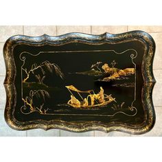 an ornately painted black and gold tray with two people on a boat in the water