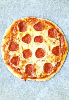 a pizza sitting on top of a table covered in cheese and pepperoni toppings