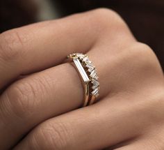 a woman's hand with a gold and white diamond ring on her left hand