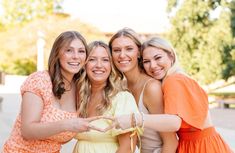 four women are posing for the camera with their arms around each other