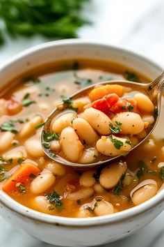 a spoon full of white bean soup with carrots and parsley