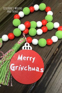 a green and red christmas ornament next to a string of beads on a wooden table