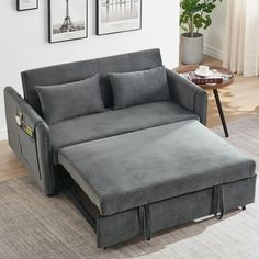 a grey couch with pull out bed underneath it in a living room next to a coffee table