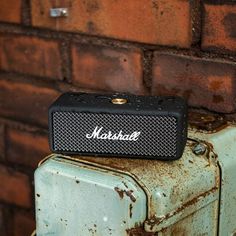 an old suitcase sitting next to a brick wall with the word marshall written on it