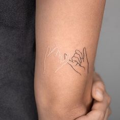 a woman's arm with a tattoo on it that says love and two hands holding each other