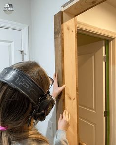 a girl wearing a blindfold is looking into a mirror with her hands on the door