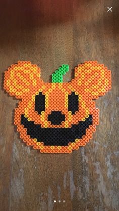 a mickey mouse made out of legos on top of a wooden floor with an orange pumpkin in the middle