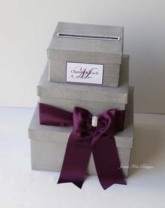 three gray boxes with purple ribbons on them are stacked next to each other and one is empty