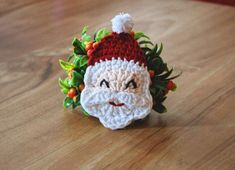 a crocheted santa claus ornament sitting on top of a wooden table