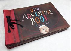 an old book with the words our adventure book written on it and a black ribbon