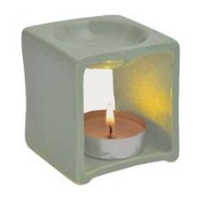 a small white candle holder with a lit candle in it