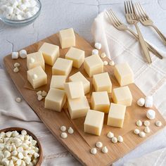 a wooden cutting board topped with cheese and marshmallows