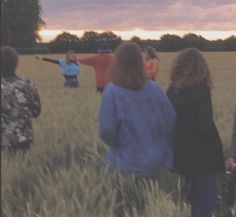 four people standing in a field watching the sun set