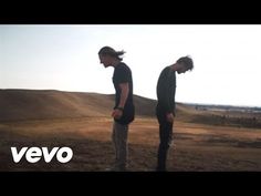 two young men standing on top of a dry grass covered field