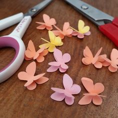 scissors and paper butterflies sitting on a table next to some cut up pieces of paper