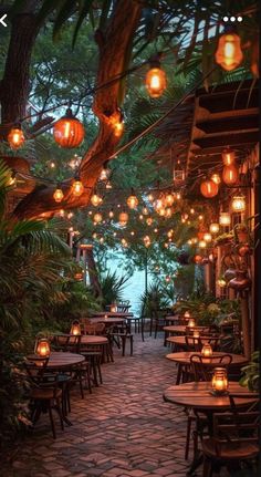 an outdoor dining area with lanterns hanging from the ceiling and tables set up for dinner