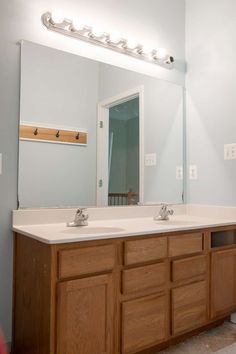 a bathroom with two sinks and a large mirror above the sink is lit by lights