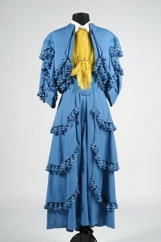 a blue dress with ruffles and a yellow tie on a mannequin