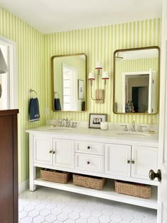 a bathroom with yellow and white striped wallpaper, two sinks, large mirrors, and wicker baskets