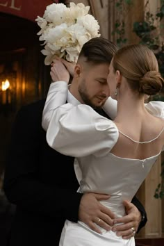 a man in a tuxedo and woman in a wedding dress embracing each other